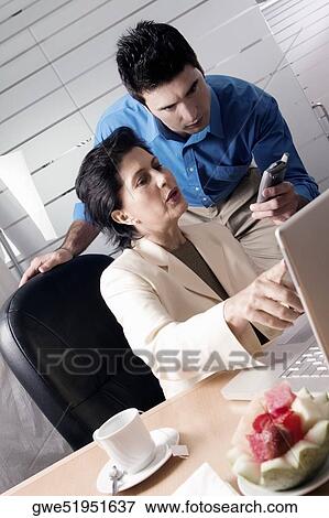 Businesswoman holding a mobile phone with a businessman standing behind her View Large Photo Image Stock Photo - Businesswoman holding a mobile phone with a businessman standing behind her. Fotosearch