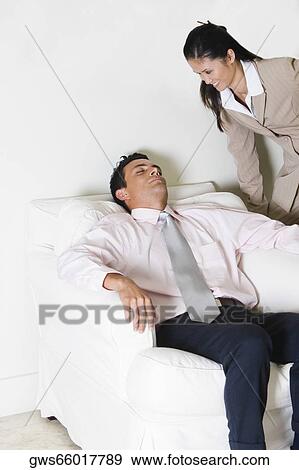 Businesswoman looking at a businessman sitting on a couch View Large Photo Image Stock Photo - Businesswoman looking at a businessman sitting on a couch. Fotosearch