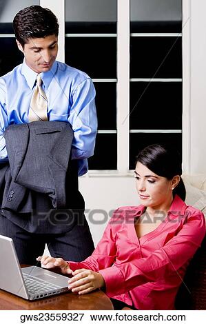 Businesswoman sitting in front of a laptop with a businessman looking at her View Large Photo Image Stock Photo - Businesswoman sitting in front of a laptop with a businessman looking at her. Fotosearch
