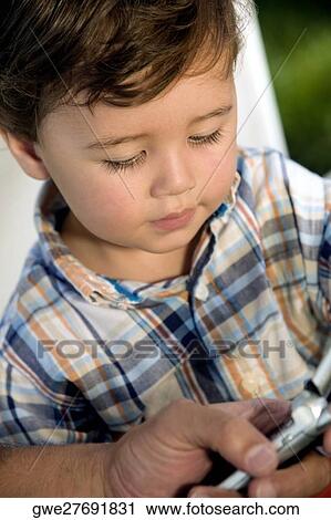 Close-up of a boy looking at a mobile phone View Large Photo Image Stock Image - Close-up of a boy looking at a mobile phone. Fotosearch