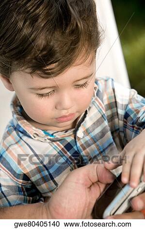 Close-up of a boy looking at a mobile phone View Large Photo Image Stock Image - Close-up of a boy looking at a mobile phone. Fotosearch