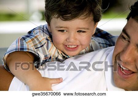 Close-up of a boy riding piggyback on his father View Large Photo Image Stock Photograph - Close-up of a boy riding piggyback on his father. Fotosearch