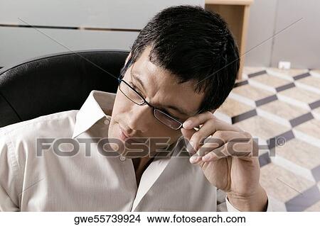 Picture - Close-up of a businessman adjusting his eyeglasses. Fotosearch