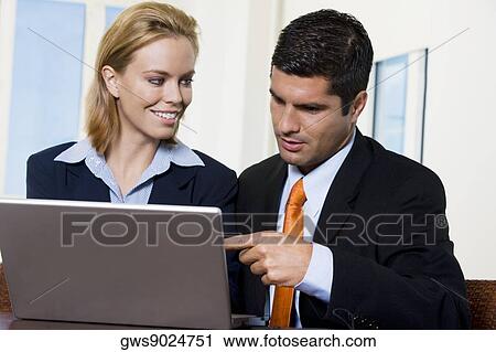 Close-up of a businessman and a businesswoman working on a laptop View Large Photo Image Stock Image - Close-up of a businessman and a businesswoman working on a laptop. Fotosearch