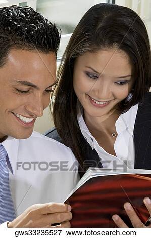 Close-up of a businessman and a businesswoman reading a book View Large Photo Image Stock Photo - Close-up of a businessman and a businesswoman reading a book. Fotosearch