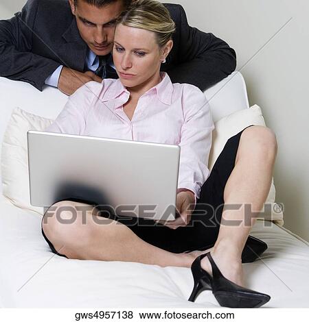 Stock Photo - Close-up of a businessman and a businesswoman looking at a laptop. Fotosearch