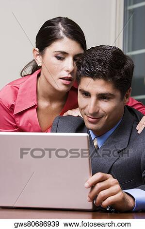 Stock Photo - Close-up of a businessman and a businesswoman using a laptop. Fotosearch