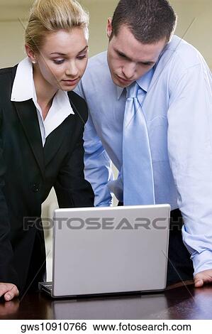 Close-up of a businessman and a businesswoman looking at a laptop View Large Photo Image Stock Photograph - Close-up of a businessman and a businesswoman looking at a laptop. Fotosearch