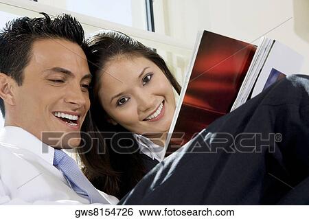 Stock Photograph - Close-up of a businessman and a businesswoman reading a magazine. Fotosearch