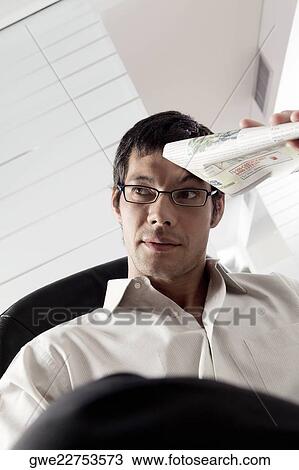 Close-up of a businessman holding a newspaper View Large Photo Image Stock Image - Close-up of a businessman holding a newspaper. Fotosearch