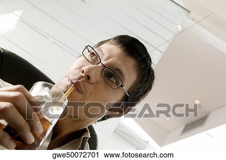Stock Image - Close-up of a businessman sipping a drink with a straw. Fotosearch