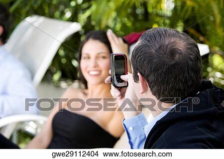 Close-up of a businessman taking a picture of a businesswoman View Large Photo Image Picture - Close-up of a businessman taking a picture of a businesswoman. Fotosearch