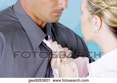 Stock Image - Close-up of a businesswoman adjusting a businessman's tie. Fotosearch