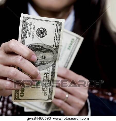 Close-up of a businesswoman holding one hundred dollar bills View Large Photo Image Stock Image - Close-up of a businesswoman holding one hundred dollar bills. Fotosearch