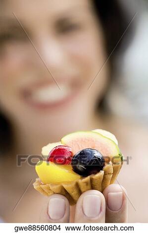 Picture - Close-up of a cupcake on a young woman's hand. Fotosearch