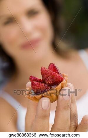 Stock Photograph - Close-up of a cupcake on a young woman's hand. Fotosearch