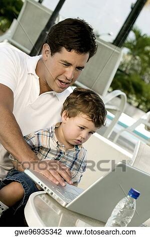 Stock Image - Close-up of a father with his son working on a laptop. Fotosearch