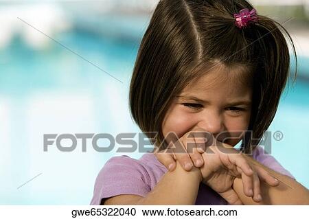 Stock Image - Close-up of a girl covering her mouth with her hands. Fotosearch