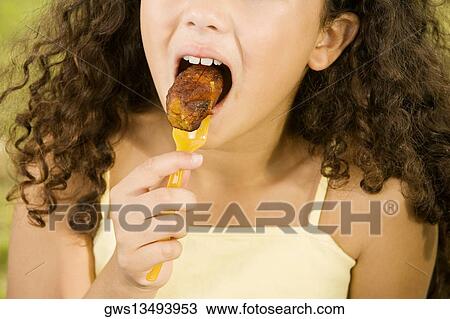 Close-up of a girl eating a piece of roast meat View Large Photo Image Stock Image - Close-up of a girl eating a piece of roast meat. Fotosearch