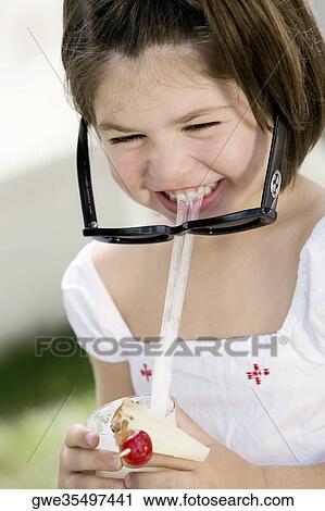 Stock Image - Close-up of a girl sipping drink from a glass. Fotosearch
