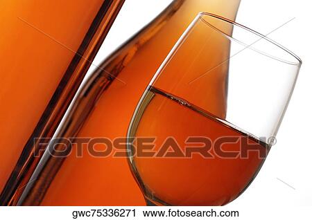 Stock Image - Close-up of a glass of wine with two wine bottles. Fotosearch
