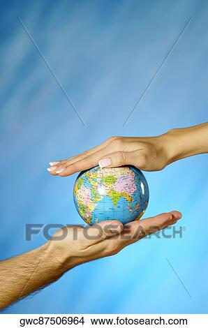 Picture - Close-up of a man and a woman's hands holding a globe. Fotosearch