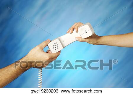 Stock Image - Close-up of a man and a woman's hands holding a telephone receiver. Fotosearch