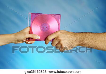 Stock Image - Close-up of a man and a woman's hands holding a compact disk. Fotosearch