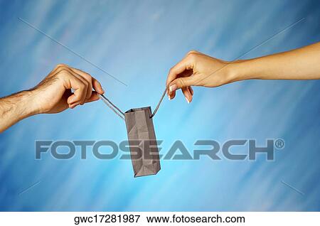 Stock Photo - Close-up of a man and a woman's hands holding a shopping bag. Fotosearch