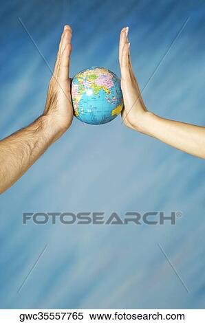 Stock Photography - Close-up of a man and a woman's hands holding a globe. Fotosearch