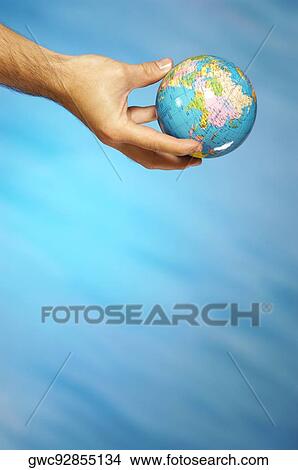 Picture - Close-up of a man's hand holding a globe. Fotosearch