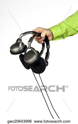 Stock Photograph - Close-up of a man's hand holding two pairs of headphones. Fotosearch