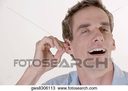Close-up of a mid adult man cleaning his ear with a cotton swab View Large Photo Image Stock Image - Close-up of a mid adult man cleaning his ear with a cotton swab. Fotosearch