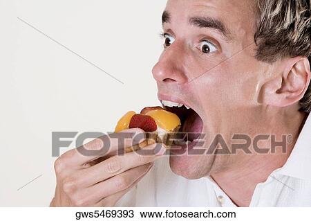 Close-up of a mid adult man eating a fruit tart View Large Photo Image Stock Image - Close-up of a mid adult man eating a fruit tart. Fotosearch