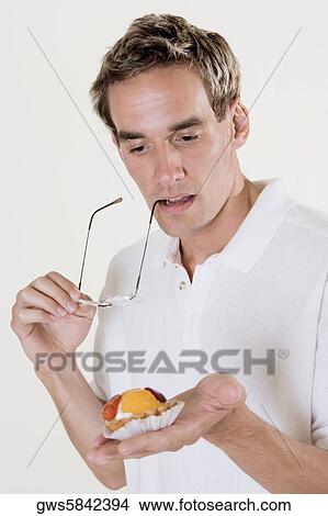 Close-up of a mid adult man holding a fruit tart and eyeglasses View Large Photo Image Picture - Close-up of a mid adult man holding a fruit tart and eyeglasses. Fotosearch