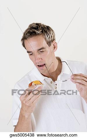 Close-up of a mid adult man holding a fruit tart and eyeglasses View Large Photo Image Stock Photo - Close-up of a mid adult man holding a fruit tart and eyeglasses. Fotosearch