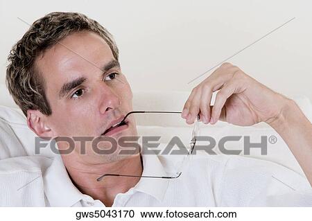 Close-up of a mid adult man holding his eyeglasses View Large Photo Image Stock Image - Close-up of a mid adult man holding his eyeglasses. Fotosearch