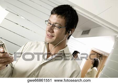 Close-up of a mid adult man listening to an MP3 Player View Large Photo Image Stock Image - Close-up of a mid adult man listening to an MP3 Player. Fotosearch