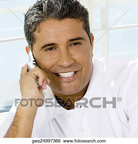 Stock Photograph - Close-up of a mid adult man talking on a mobile phone. Fotosearch