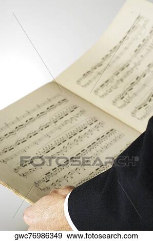 Stock Photo - Close-up of a musician's hand holding sheet music. Fotosearch
