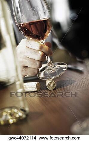 Picture - Close-up of a person's hand holding a glass of wine. Fotosearch