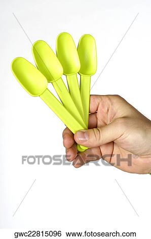 Stock Photograph - Close-up of a person's hand holding four plastic spoons. Fotosearch