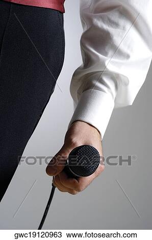 Stock Image - Close-up of a singer's hand holding a microphone. Fotosearch