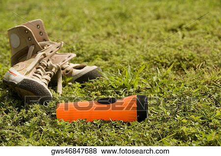 Close-up of a torch light near a pair of shoes lying on the grass View Large Photo Image Stock Photo - Close-up of a torch light near a pair of shoes lying on the grass. Fotosearch