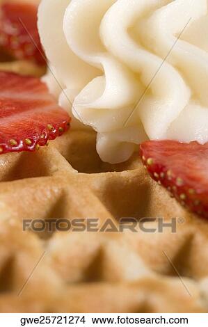 Close-up of a waffle with whipped cream and strawberry slice on it View Large Photo Image Picture - Close-up of a waffle with whipped cream and strawberry slice on it. Fotosearch