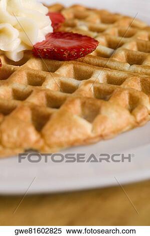 Close-up of a waffle with whipped cream and strawberry slice on it View Large Photo Image Stock Photography - Close-up of a waffle with whipped cream and strawberry slice on it. Fotosearch