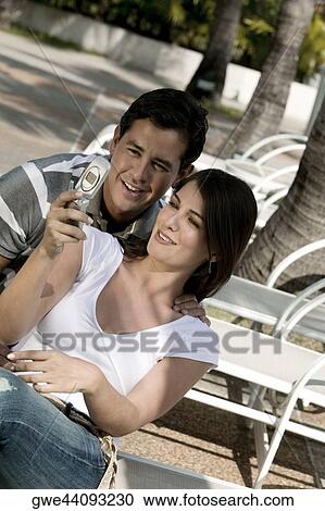 Close-up of a young couple looking at a mobile phone View Large Photo Image Stock Image - Close-up of a young couple looking at a mobile phone. Fotosearch