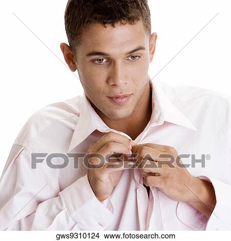 Close-up of a young man buttoning his shirt View Large Photo Image Picture - Close-up of a young man buttoning his shirt. Fotosearch