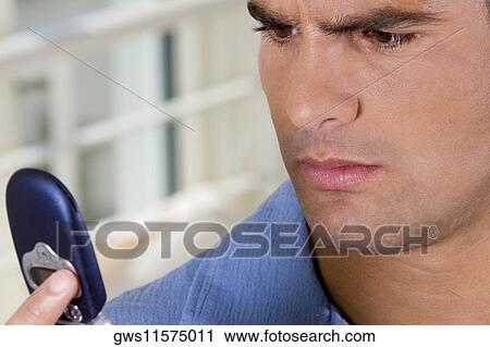 Close-up of a young man holding a mobile phone View Large Photo Image Stock Image - Close-up of a young man holding a mobile phone. Fotosearch