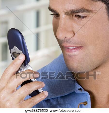 Close-up of a young man holding a mobile phone View Large Photo Image Stock Image - Close-up of a young man holding a mobile phone. Fotosearch